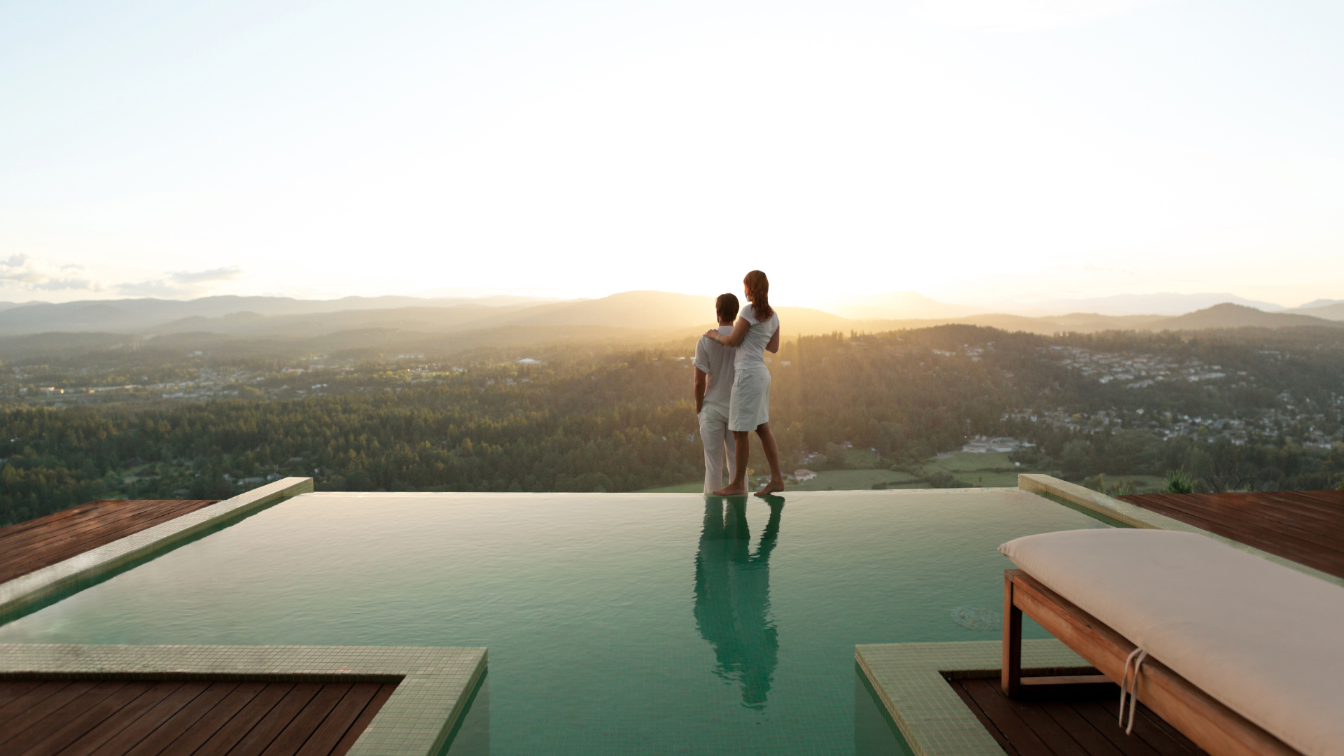 Image of a couple standing in front of a pool overlooking a valley